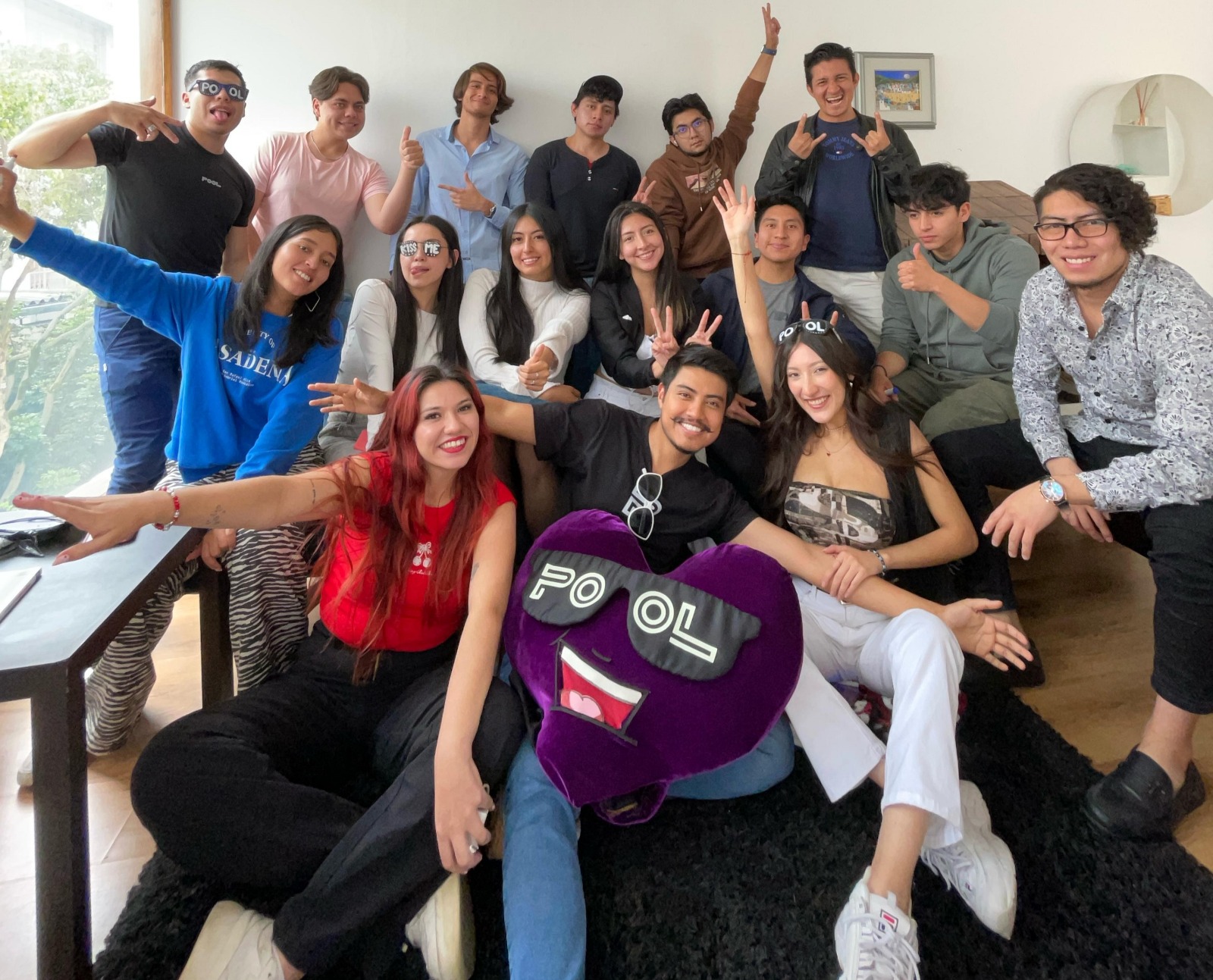 El equipo de la startup ecuatoriana POOL posando sonriente con su mascota de felpa morada.